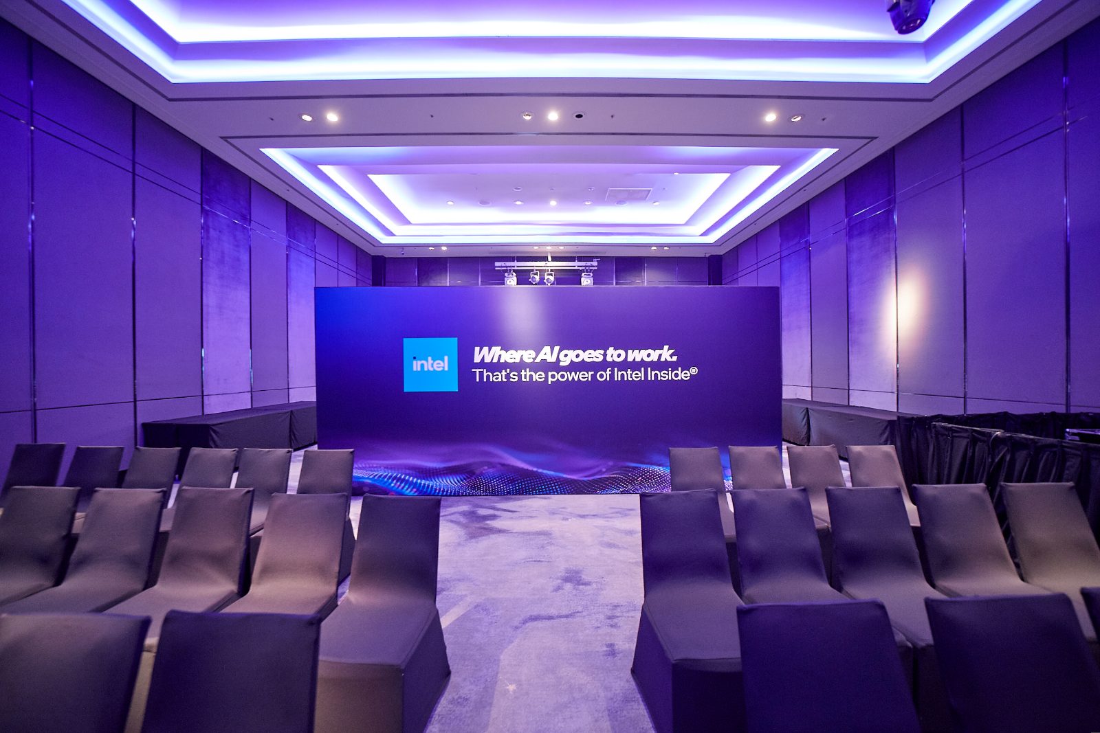The briefing room stage with a Where AI goes to work backdrop and rows of seating under cove lighting